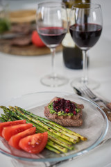 Gourmet steak with grilled asparagus  and glass of red wine on white table
