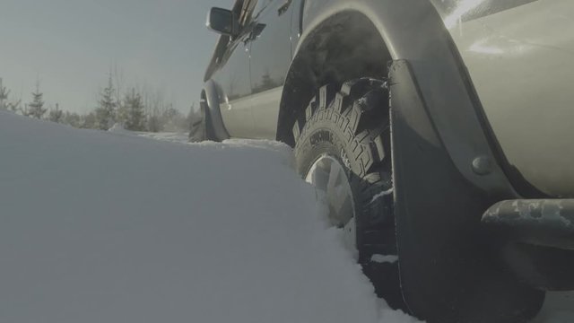 Driving SUV car in winter on forest road with much snow. Car stuck in the woods. Closeup