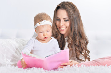 Beautiful young mother with daughter reading book