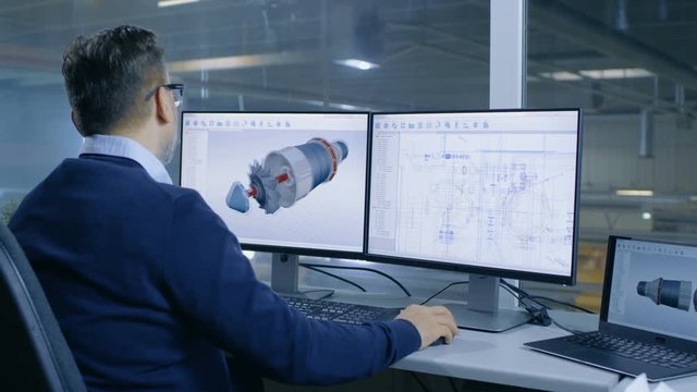  Chief Male Engineer Designs on 3D Model of a Turbine or Engine Part. Second Screen Shows Technical Blueprints. Out of the Office Window Big Factory is Seen.Shot on RED EPIC-W 8K Helium Cinema Camera.