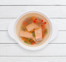 Dietary broth with vegetables and red fish. Healthy food, slim body, lunch dish concept. White wooden planks background.