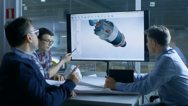Team of Industrial Engineers Discuss 3D Turbine/ Engine Part Design Shown on a Presentation Display. In the Background Factory is Seen. Shot on RED EPIC-W 8K Helium Cinema Camera.