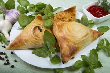 Samosa with spicy herbs on a white plate with garlic and peppers with tomato sauce