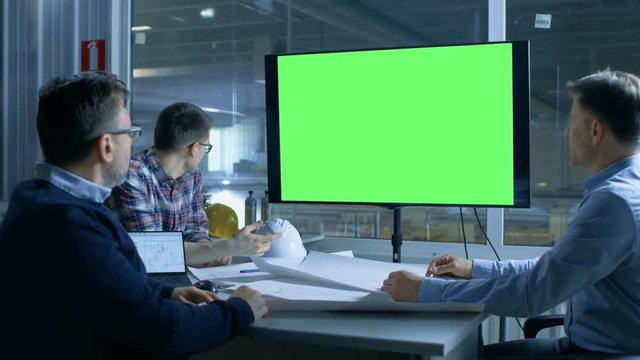 Team of Industrial Engineers Have Important Meeting. Presentation Display Shows Mock-up Green Screen. In the Background Factory is Seen.Shot on RED EPIC-W 8K Helium Cinema Camera.