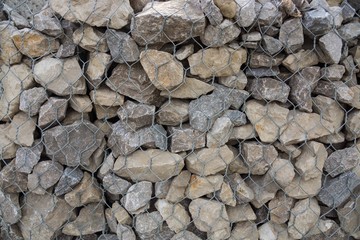 Stone wall  background or texture/.Building strengthening/Stones in the iron grid on texture