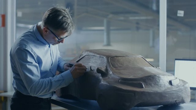 Grey Haired Automotive Designer Sculpts Futuristic  Car Model from Plasticine Clay with Wire. He Works in a Special Studio Located In a Large Car Factory. Shot on RED EPIC-W 8K Helium Cinema Camera.