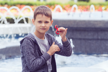 Boy with a fidget spinner sitting in city park