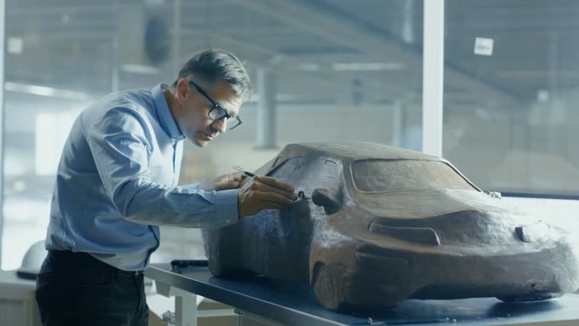 Chief Automotive Designer with Rake Sculpts Futuristic  Car Model from Plasticine Clay. He Works in a Special Studio Located In a Large Car Factory. Shot on RED EPIC-W 8K Helium Cinema Camera.