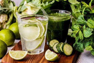 green smoothie and detox water with lime, mint and ice on wooden background. detox diet. Close-up