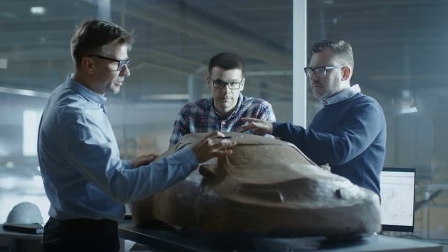 Team of Automotive Design Engineers Discusses New Prototype Design Model Made of Plasticine Clay. They Work in a Large Car Factory. Shot on RED EPIC-W 8K Helium Cinema Camera.