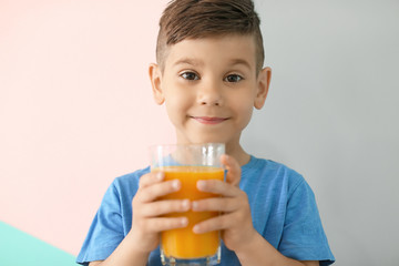Cute little boy with glass of juice on color background