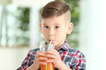 Cute little boy drinking juice at home