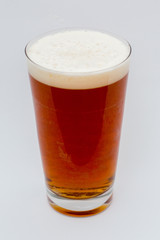 Amber Ale beer with foam in glass on a white background.