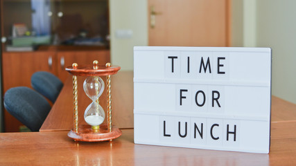 Time for lunch sign in lightbox put on the desk in office interior.
