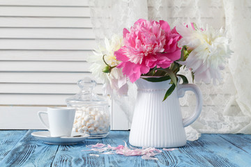 Artistic still life with peonies and cup of coffee and petals