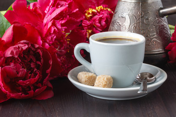 cup of coffee , pink peonies pattern on wooden background . Good morning