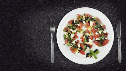 Caprese salad dish on granite countertop with copyspace on side. Top view