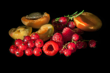 Fototapeta na wymiar Fresh fruits and berries such as apricot, raspberry red currant on a black background