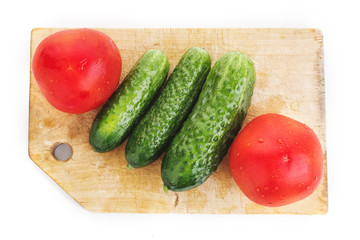 Tomatoes and cucumbers on wood cutting board isolated on white. Top view of vegetables set