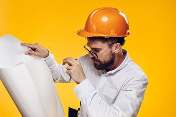 Engineer with a beard on a yellow background holds a drawing