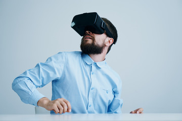 A young guy with a beard on a light background in virtual reality glasses