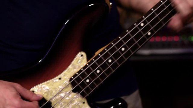 Bass guitar instrument detail and player human hands moving on body and neck