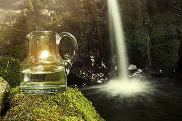 glass carafe with water and waterfall in the background