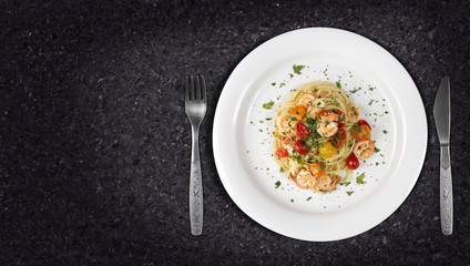 Spaghetti with shrimps or prawns dish on marble countertop with copyspace on side. Top view