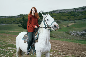 Beautiful young woman walking in the mountains riding a horse