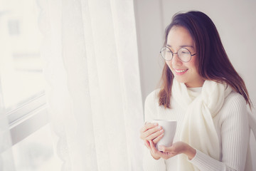 Portrait of bedroom concept: asian woman holding a cup of coffee with on bedroom in breakfast time.