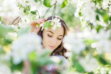 Fototapeta premium Beautiful brunette posing in blossoming apple-trees