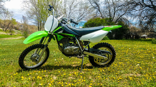 Kids 125cc Kawasaki Dirt Bike sitting in a field of grass and flowers in Wyoming on Summer Day