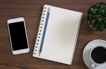 Wood office desk table with laptop computer, notebook with pen and cup of coffee.Top view