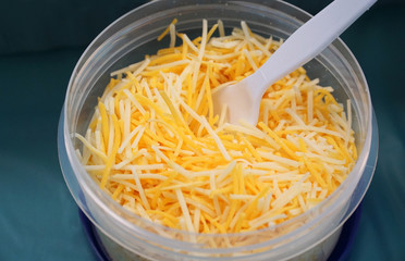 grated cheese in plastic container with fork