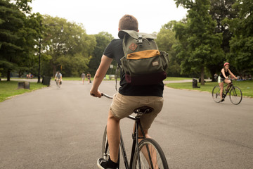 Naklejka premium Back view of modern hipster man riding bike in the park