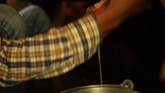 Young Indian man milks cow, close up, pan and tilt between man and teets, in Himachal Pradesh, northern India