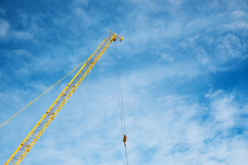 Part of yellow construction crane, on blue sky background