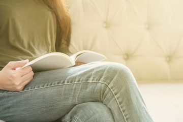 Closeup woman sitting on sofa for reading a book in free time in the afternoon , relax time of asian woman concept