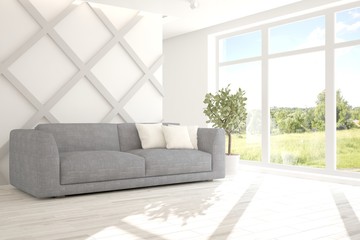 Fototapeta premium White room with sofa and green landscape in window. Scandinavian interior design. 3D illustration