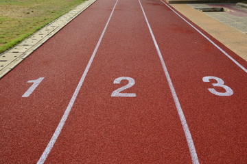 Fototapeta premium Red treadmill, track running at the stadium with green grass