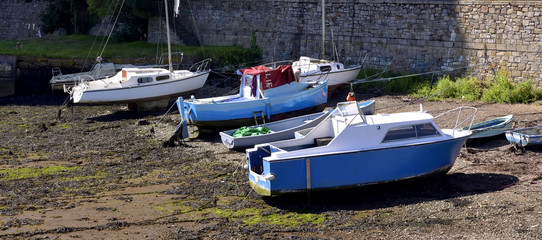 Fishing boats moored at low tide in the Cornish harbour.