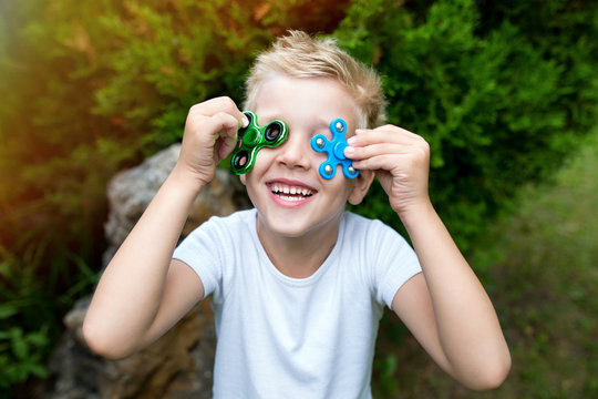 Young good mood boy close up portrait, holding in fingers two spiners. Messy hairstyle boy guy with fashion toy spinner. horizontal banner conceptual idea life style, new effects successful lifestyle
