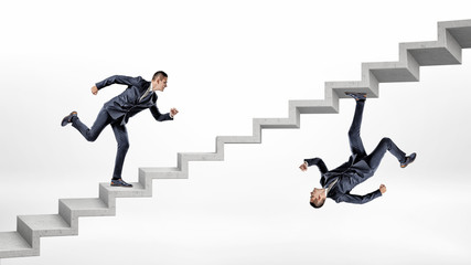 Two businessmen running up concrete stairs in overturned reflected image of each other.