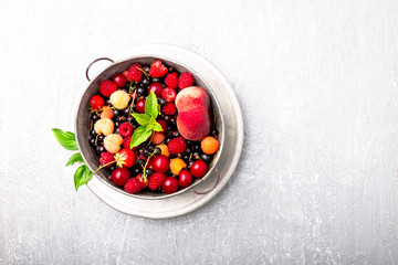 Mix fruit and berries in grey metal bowl. Top view.