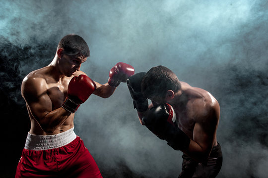 Two professional boxer boxing on black smoky background,