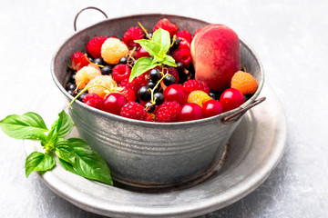 Mix fruit and berries in grey metal bowl. Close up.