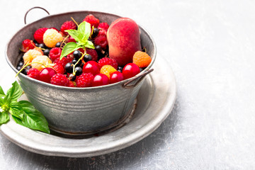 Mix fruit and berries in grey metal bowl. Close up.