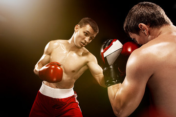 Naklejka na ściany i meble Two professional boxer boxing on black background,