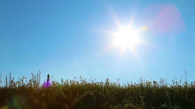 Silhouette of adult healthy man hiking during vacations. Person with backpack on back walks slowly along grassy hill at bright sunset sunlight and blue sky background. Real time full hd video footage.