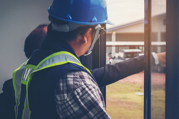 Architect and engineer discussion blueprint at construction site of new home
